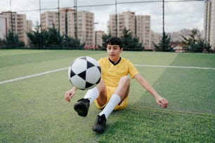 a young man sitting on the ground with a soccer ball