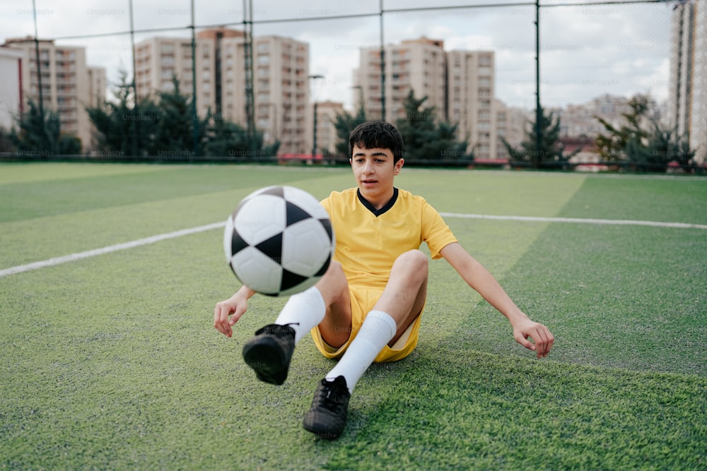 Un jeune homme assis par terre avec un ballon de soccer