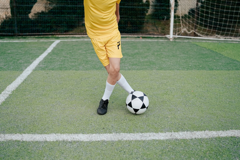 Un homme en uniforme jaune donnant un coup de pied dans un ballon de football