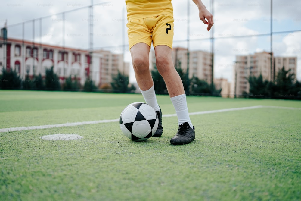 Un calciatore in uniforme gialla che calcia un pallone da calcio