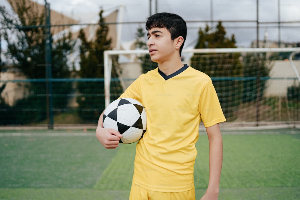 a young boy holding a soccer ball on a soccer field