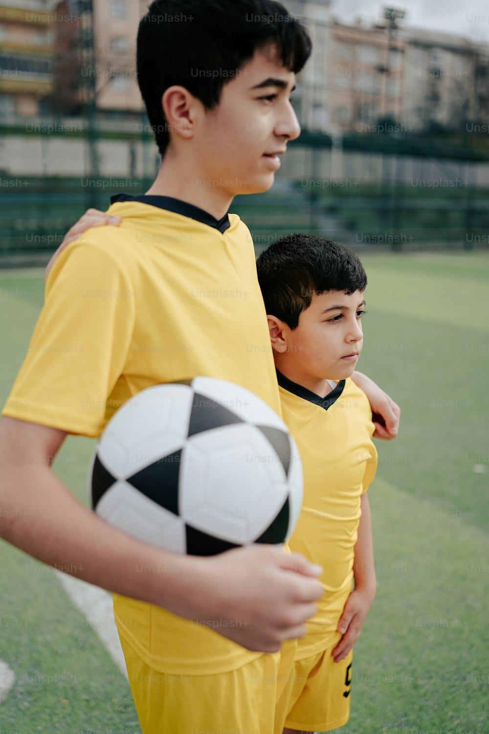 two young boys standing next to each other holding a soccer ball