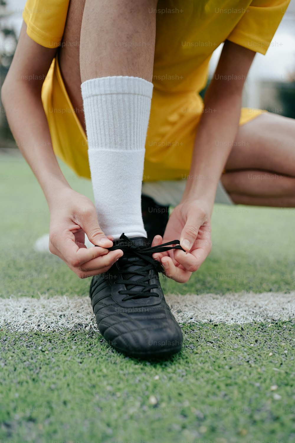 a person tying a shoelace on a soccer field