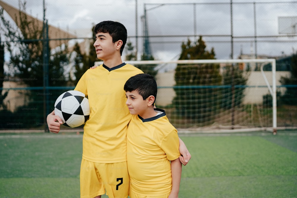 a couple of kids standing next to each other holding a soccer ball