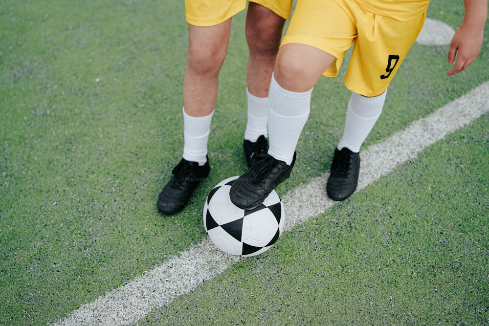 um casal de jovens de pé ao lado de uma bola de futebol