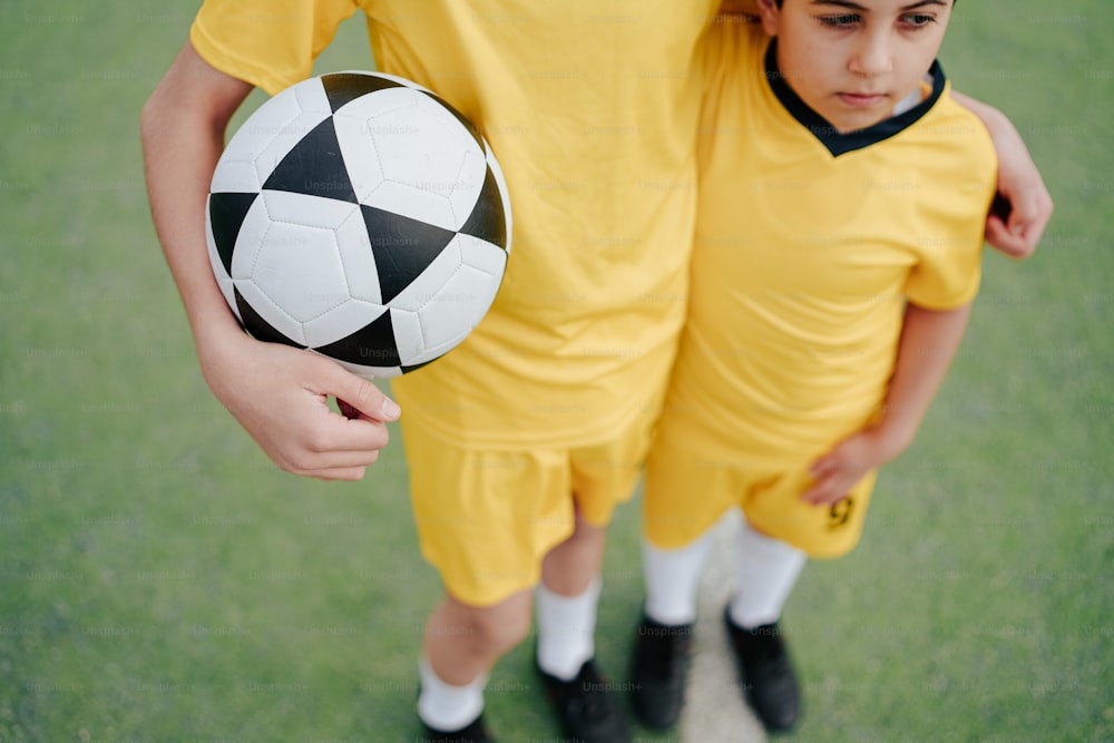 Dos niños jóvenes con uniformes de fútbol sosteniendo una pelota de fútbol