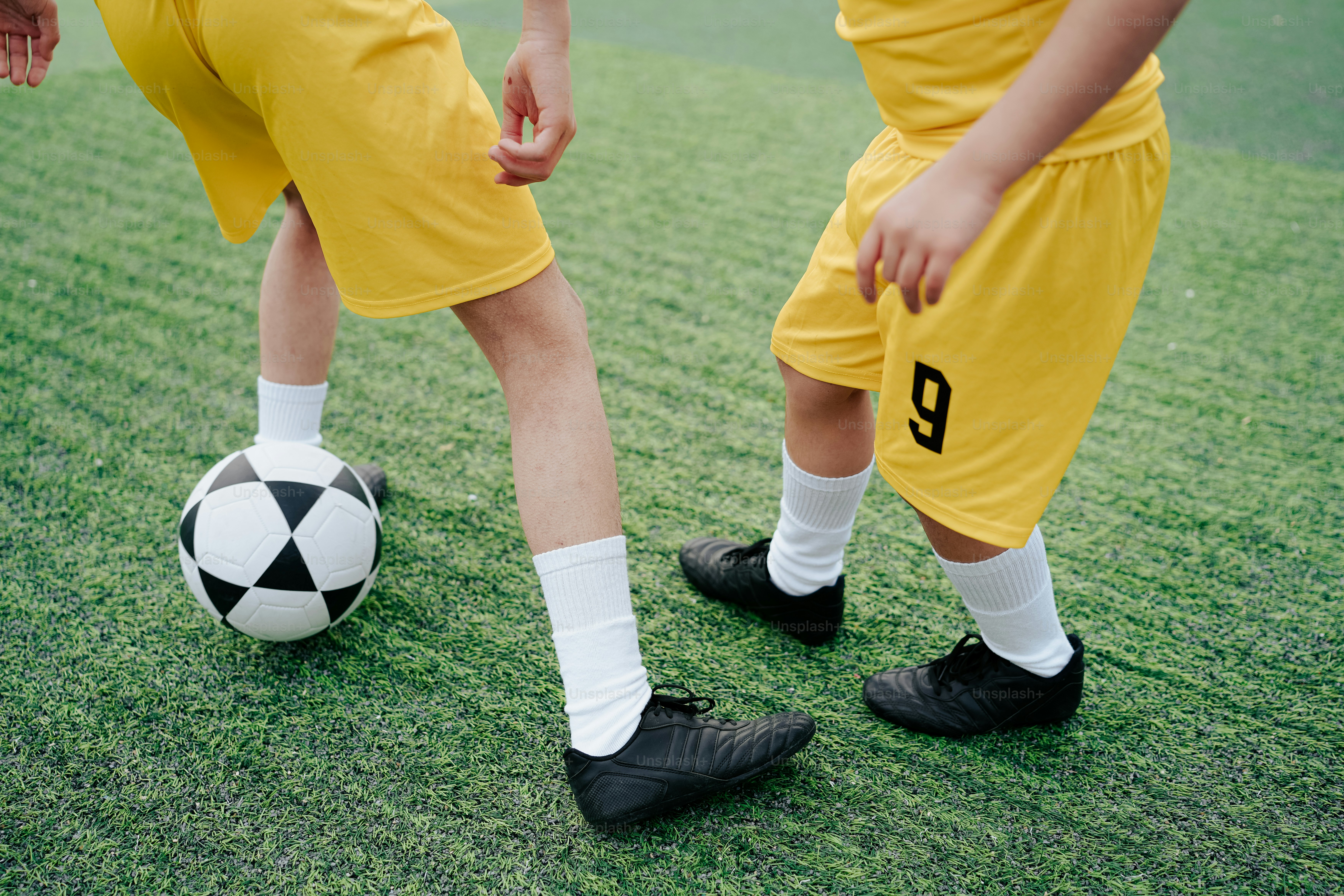 a couple of young men standing next to a soccer ball
