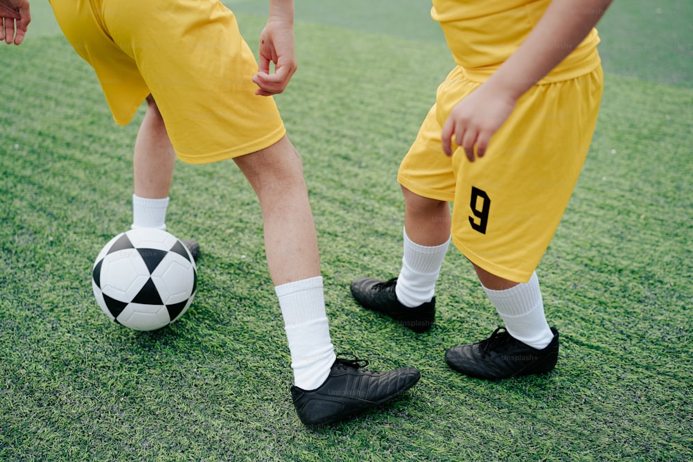Un par de jóvenes parados junto a un balón de fútbol