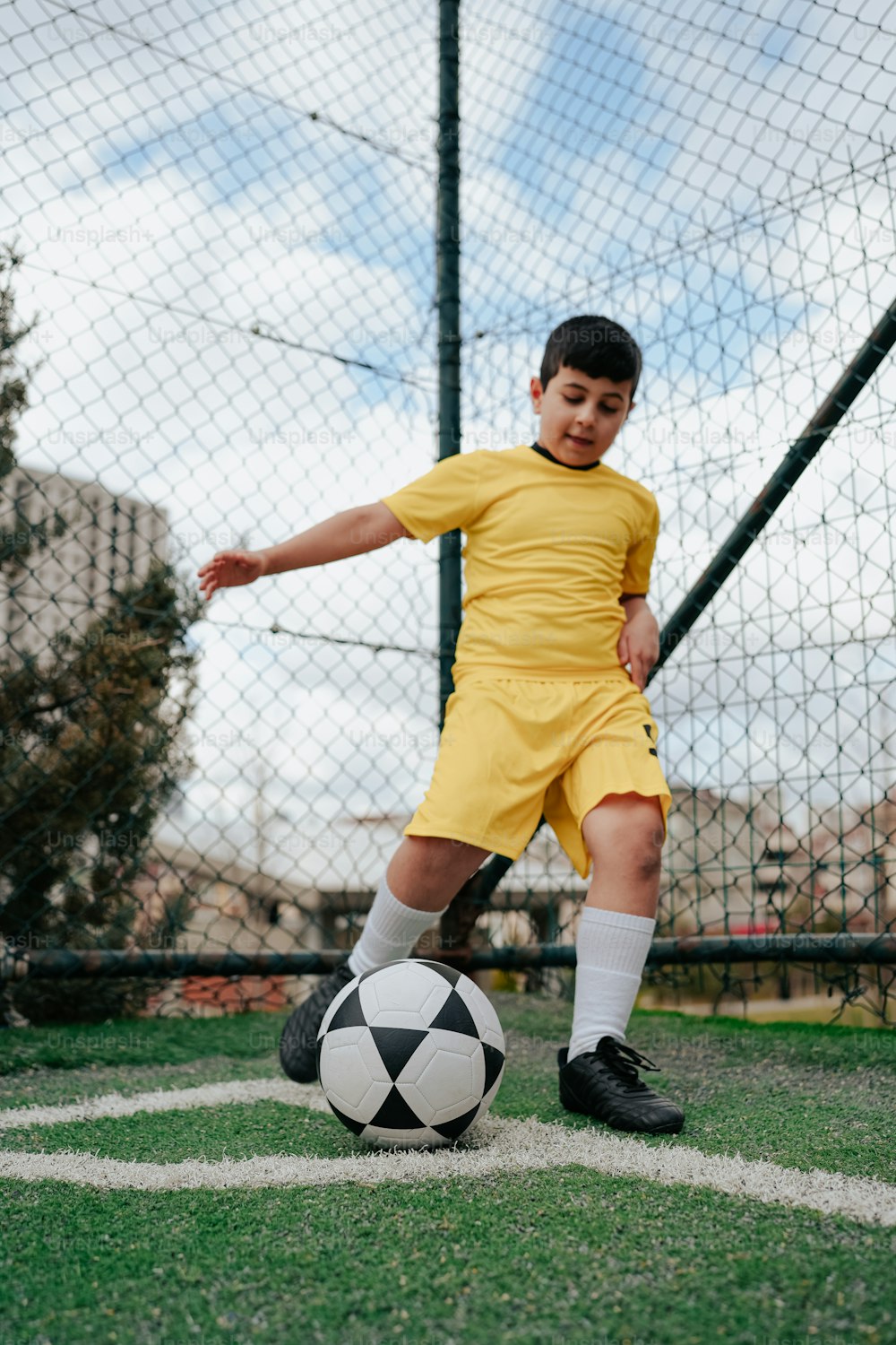 Un giovane ragazzo che calcia un pallone da calcio su un campo