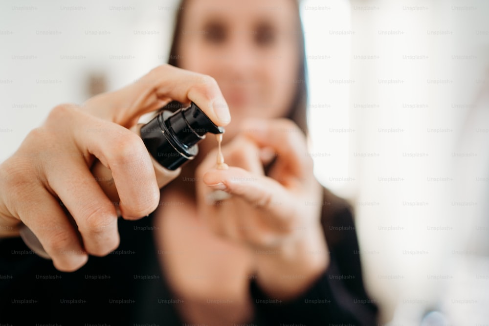 uma mulher segurando um pequeno objeto preto em sua mão