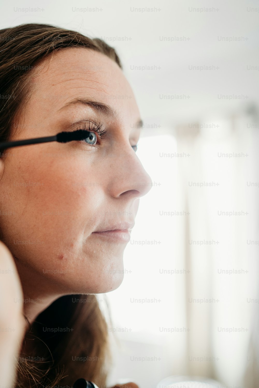 uma mulher está fazendo sua maquiagem no espelho