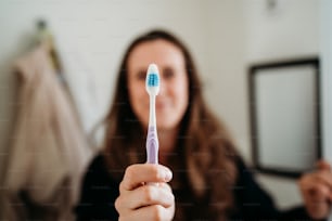 a woman holding a toothbrush in her hand