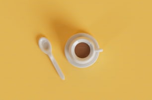 una tazza di caffè e un cucchiaio su sfondo giallo