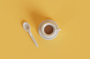 a cup of coffee and a spoon on a yellow background