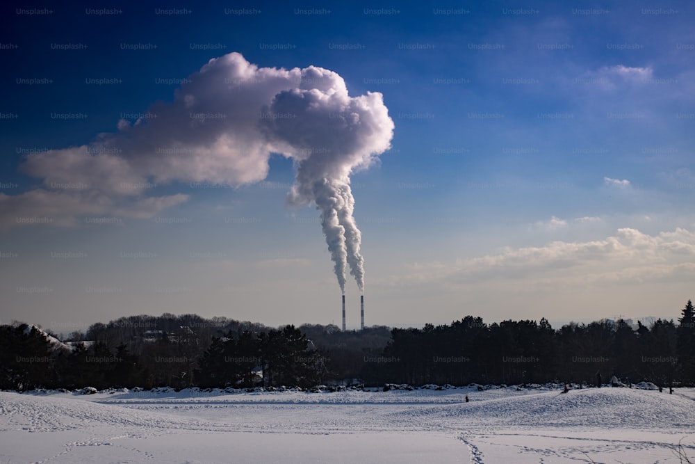 uma chaminé emite de uma fábrica em uma paisagem nevada