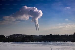 Ein Schornstein kommt aus einer Fabrik in verschneiter Landschaft