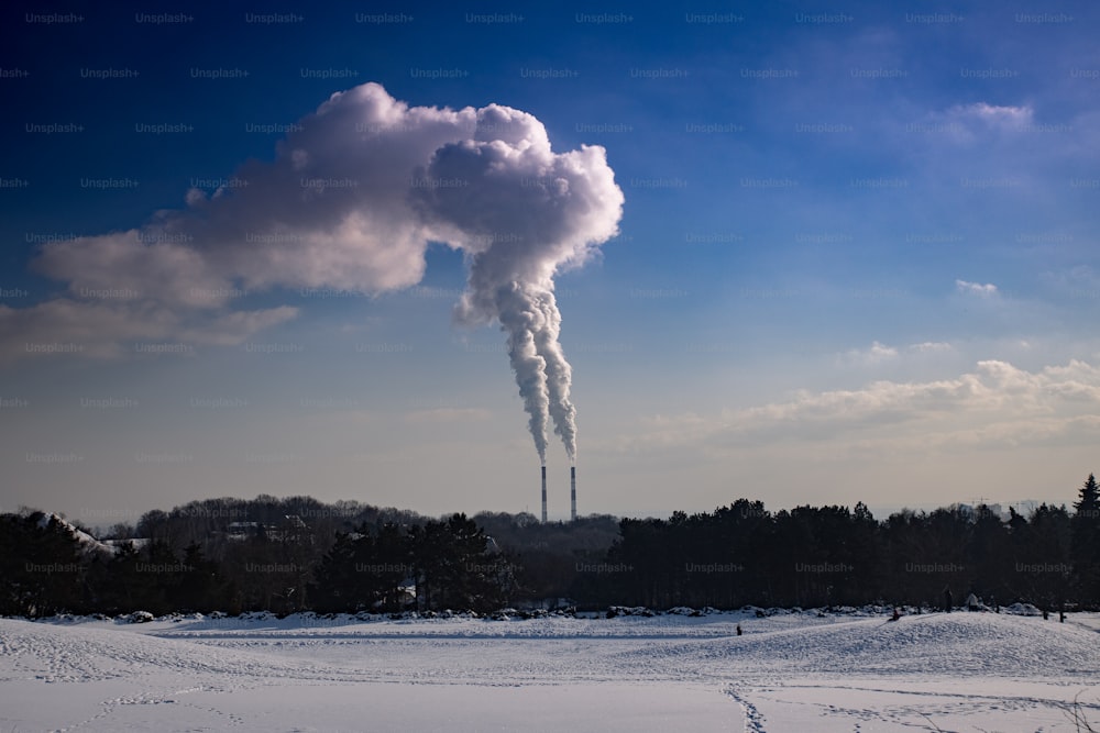 a smokestack emits from a factory in a snowy landscape