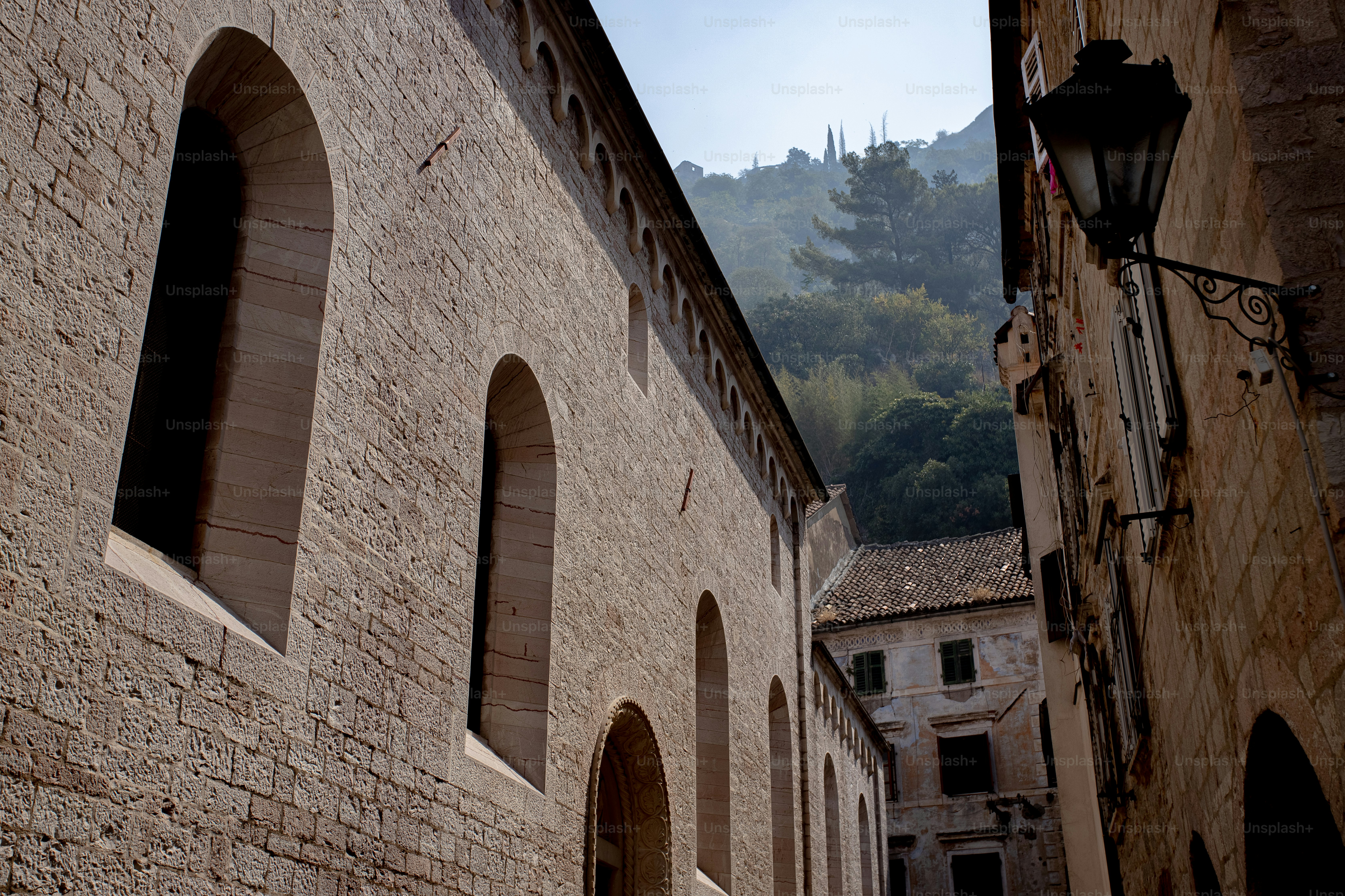 a stone building with arched windows and a mountain in the background