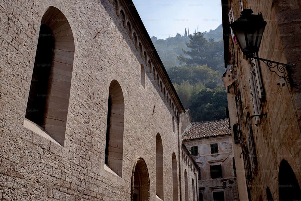 a stone building with arched windows and a mountain in the background