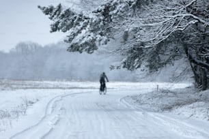 Ein Mann fährt mit dem Fahrrad eine schneebedeckte Straße hinunter
