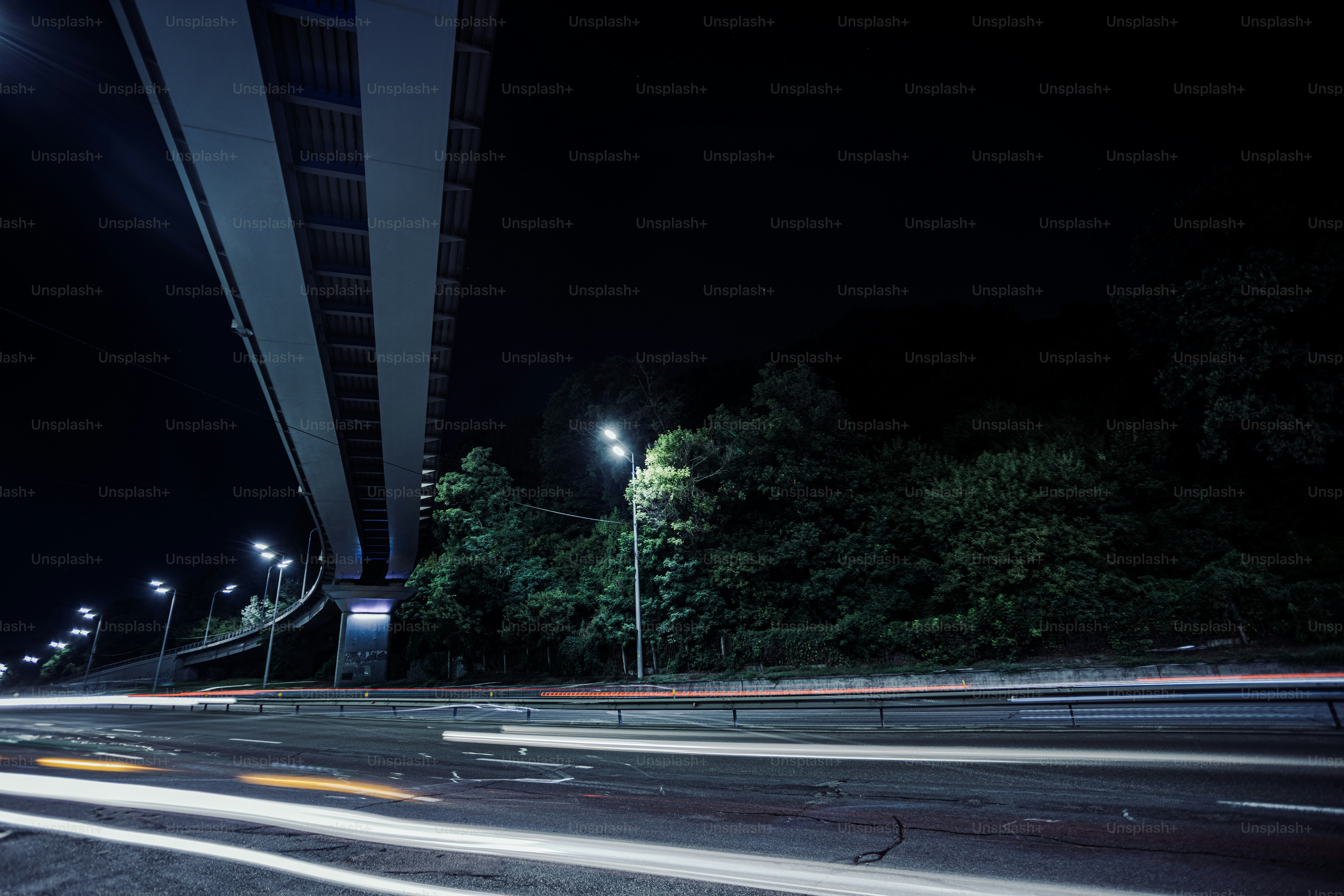 a city street at night with a bridge in the background