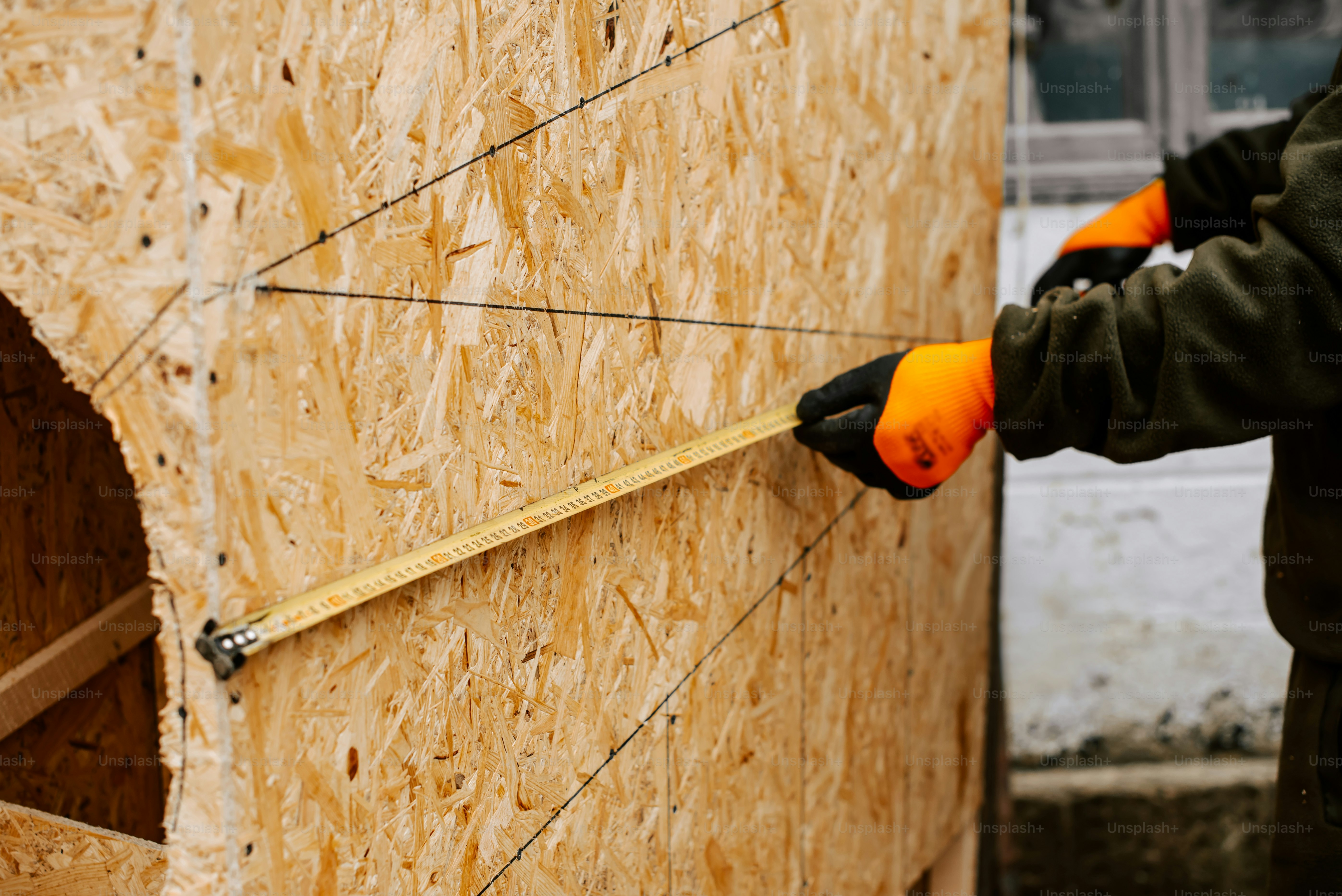 Un uomo che misura l'altezza di una struttura di legno