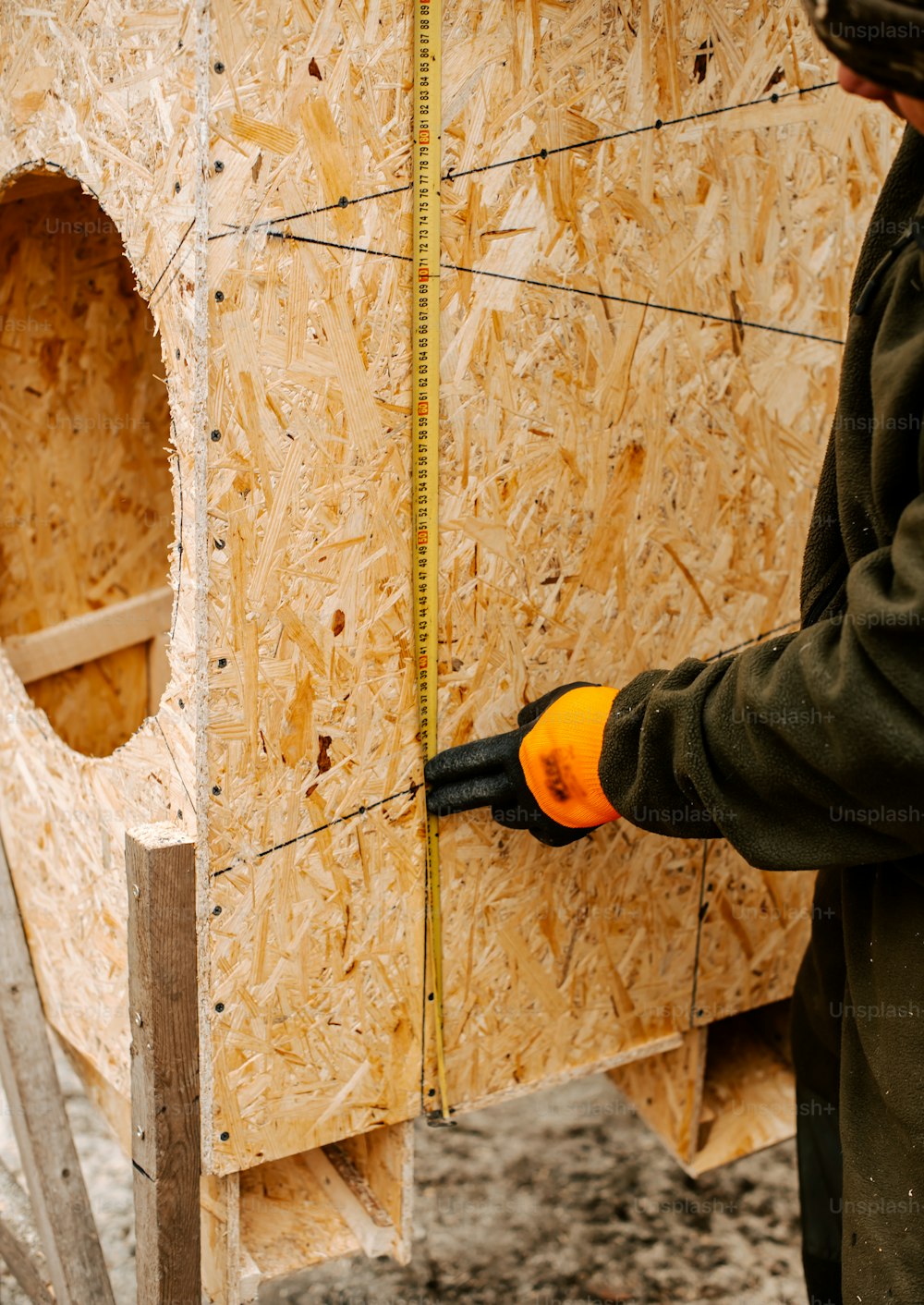 Ein Mann hält eine Schere vor einer Holzkonstruktion