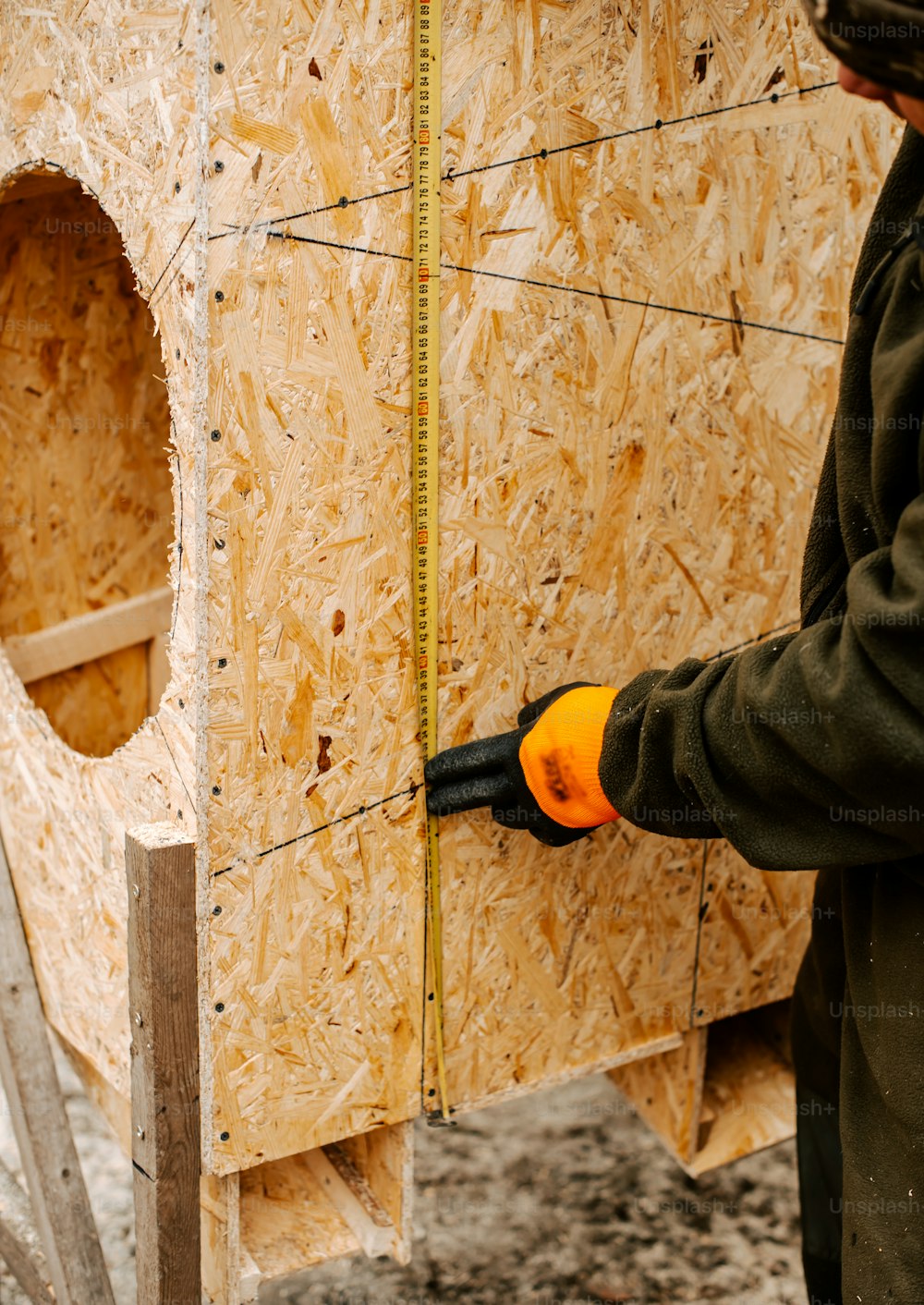 um homem segurando um par de tesouras na frente de uma estrutura de madeira