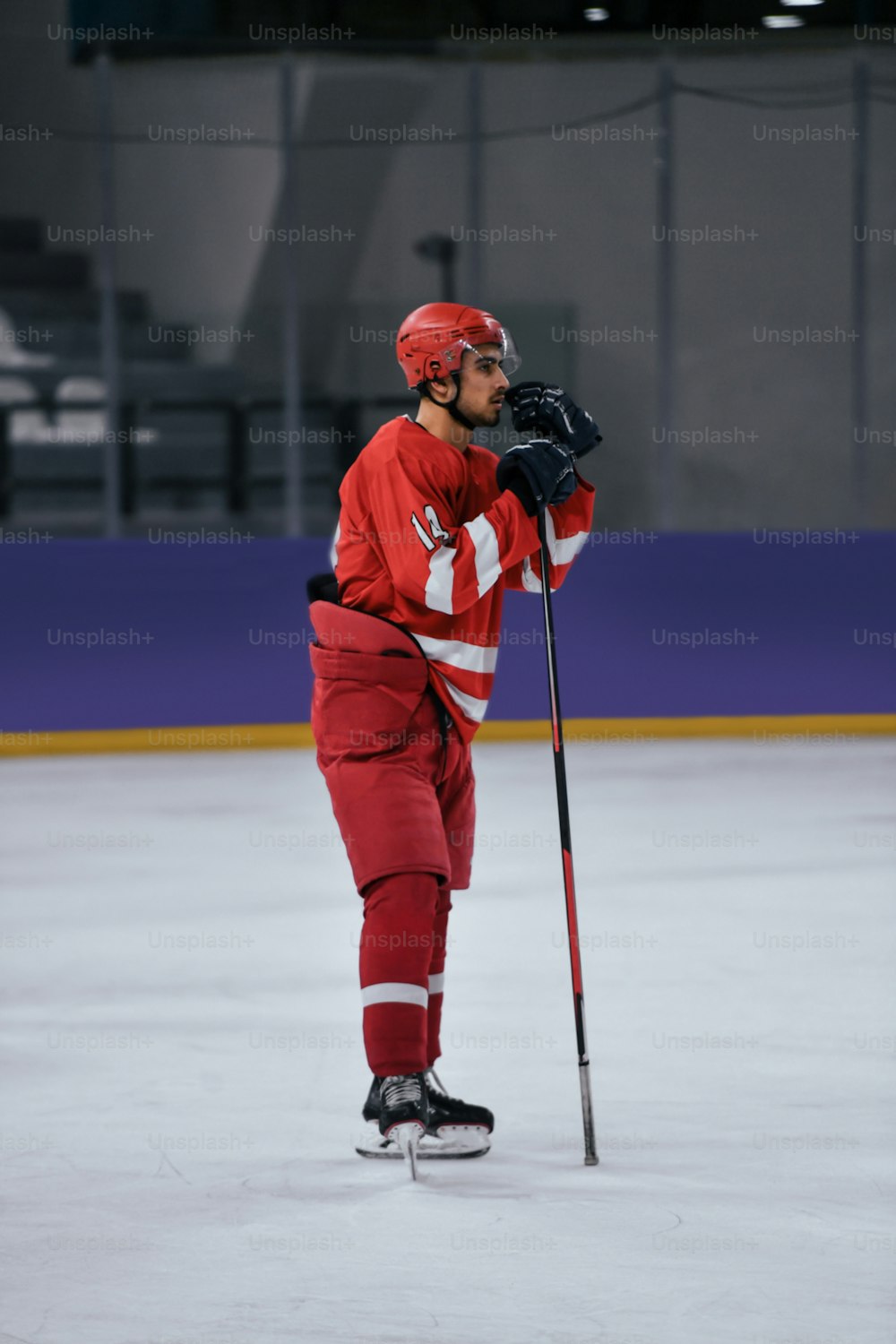 Ein Mann in roter Hockeyuniform mit einem Hockeyschläger