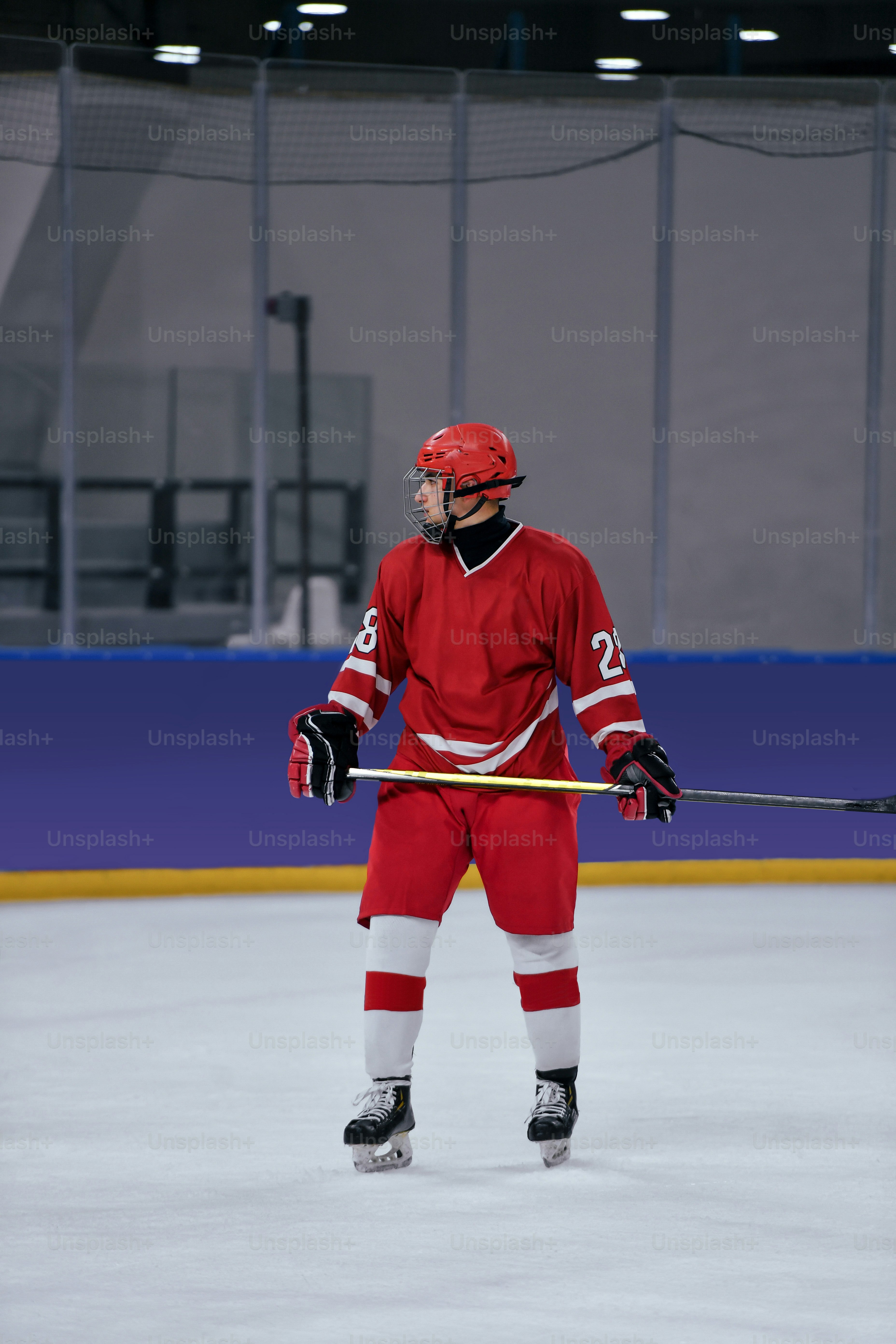 Un hombre con un uniforme rojo de hockey sosteniendo un palo