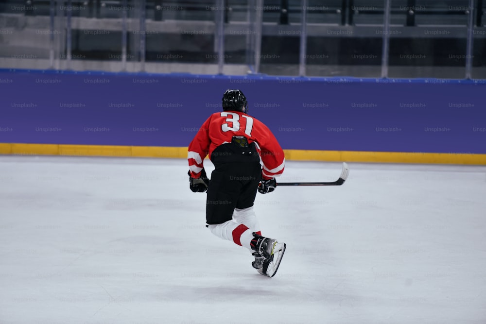 Un hombre con una camiseta roja patinando en una pista de hielo