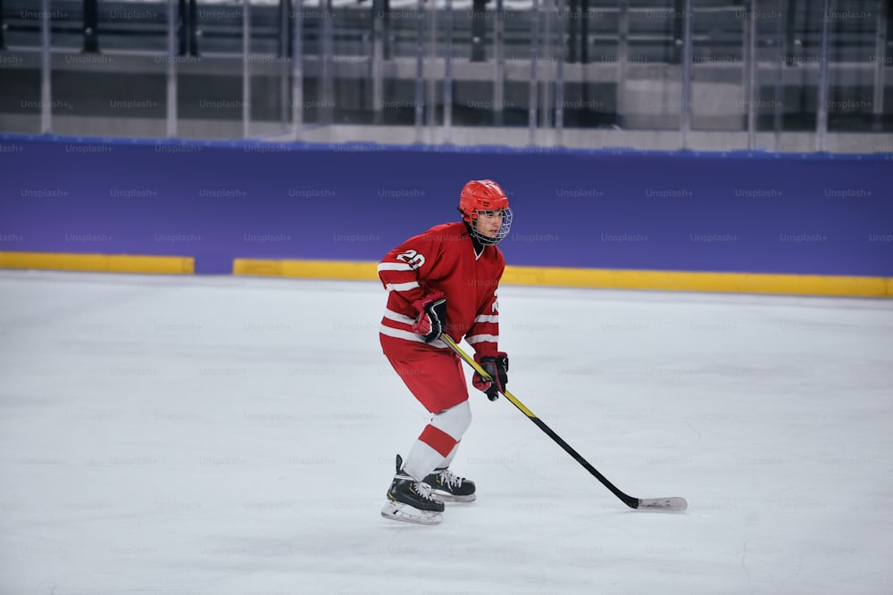 um homem em um uniforme de hóquei vermelho patinando em uma pista de gelo