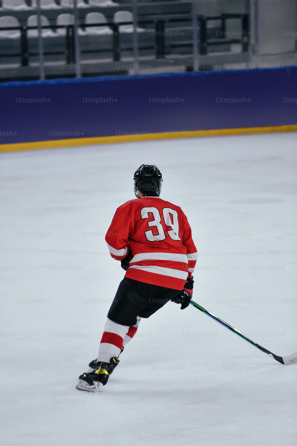 a hockey player in a red jersey skating on an ice rink