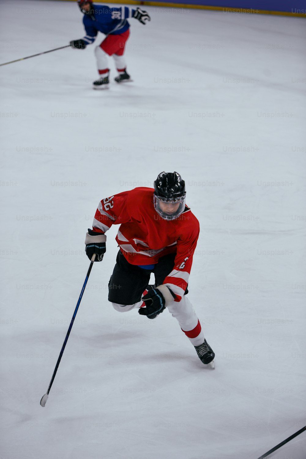 um homem em uma camisa vermelha patinando em uma pista de gelo