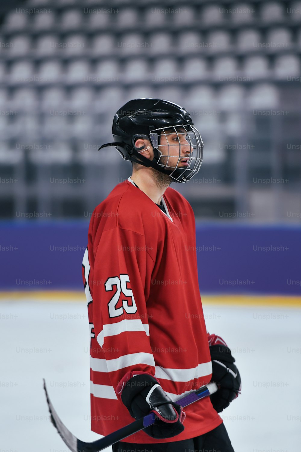Ein Mann im roten Trikot hält einen Hockeyschläger in der Hand