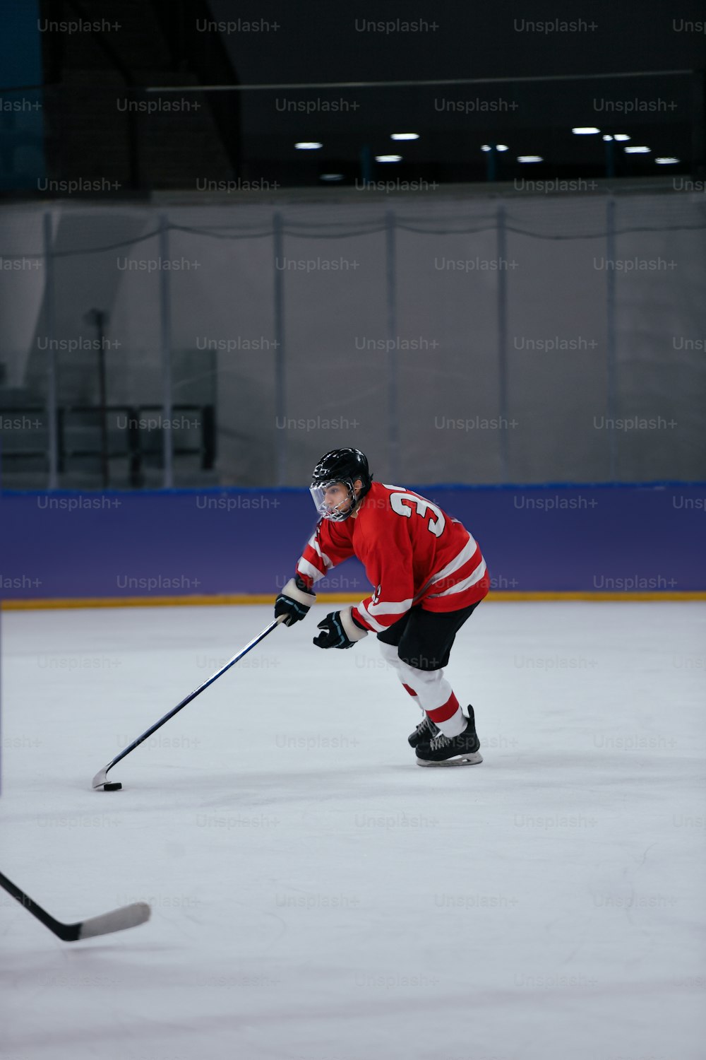 Un hombre con una camiseta roja patinando en una pista de hielo