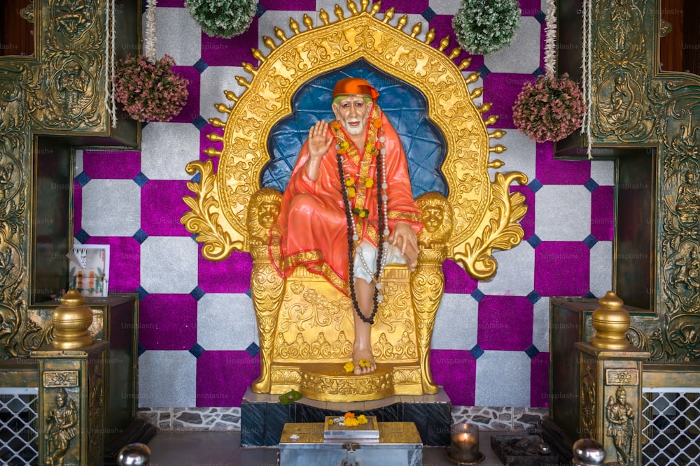 Una statua di un uomo seduto sulla cima di un trono d'oro