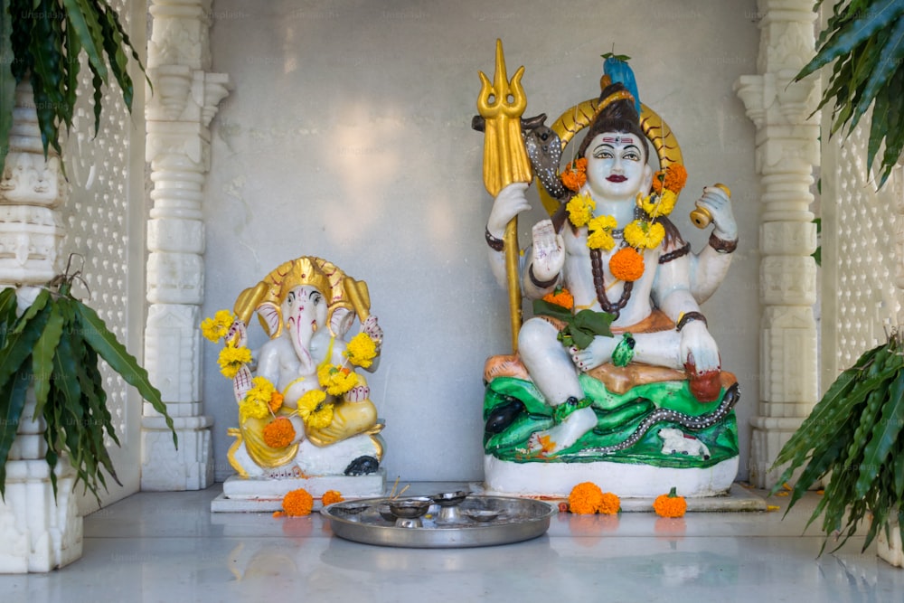 Una estatua de un dios hindú y una planta en maceta