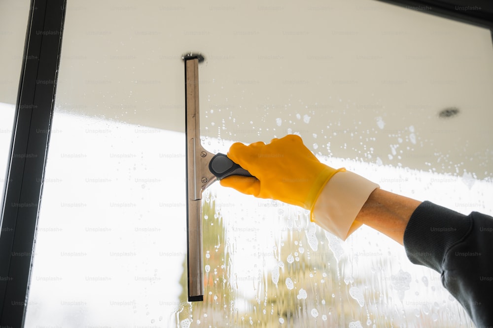 a person wearing yellow gloves and rubber gloves is holding a window sealer