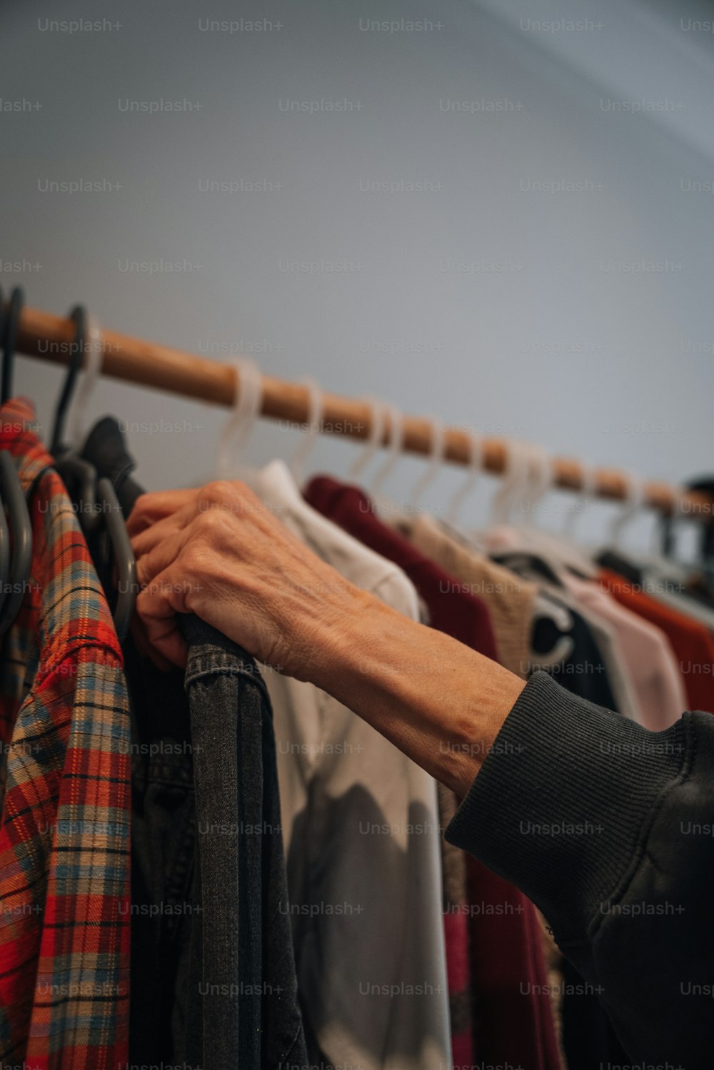 a woman's hand on a rack of clothes
