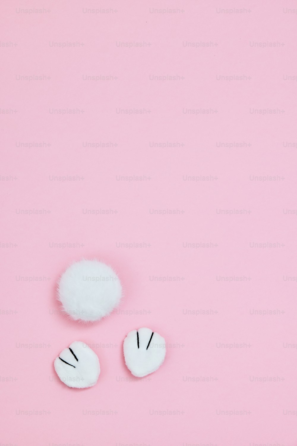 a pink background with two white fluffy balls