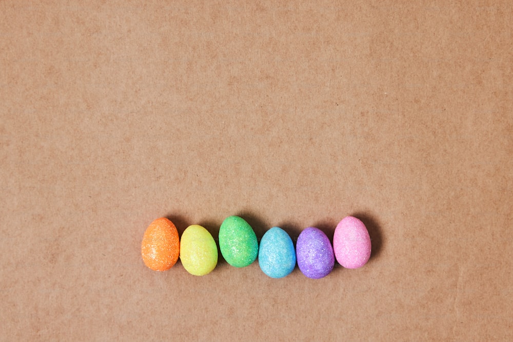 una fila di uova colorate sedute sopra un tavolo