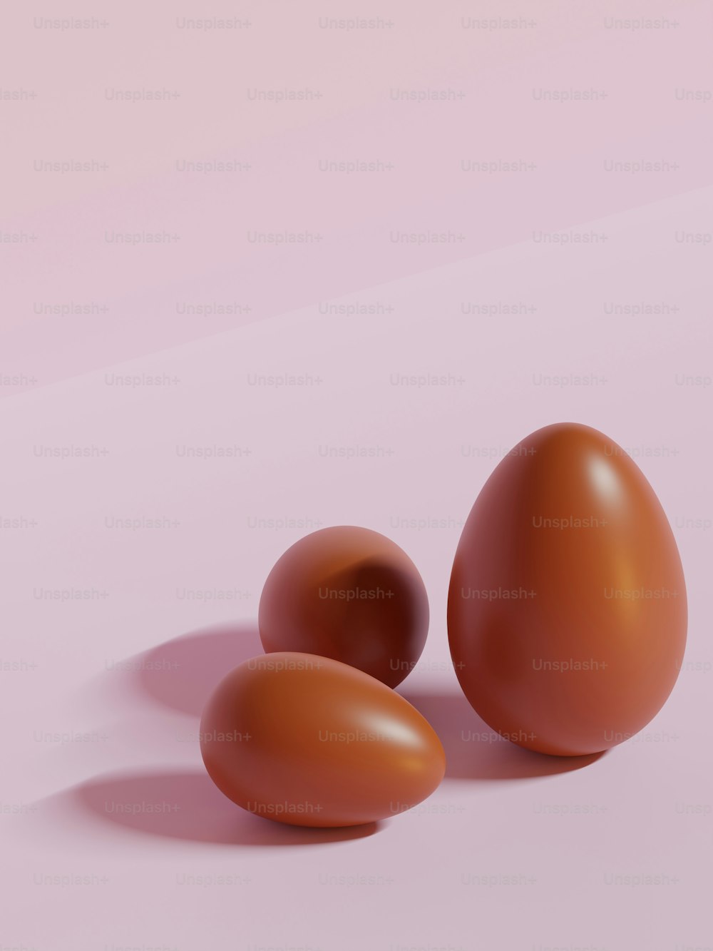 three brown eggs on a pink background