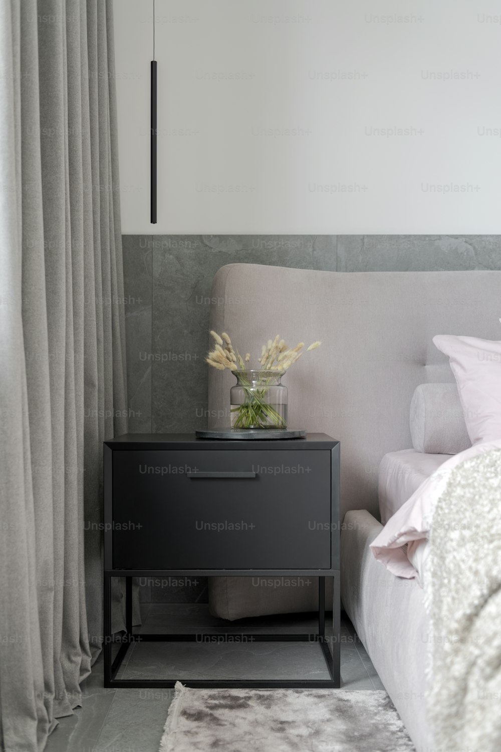 a nightstand with a vase of flowers on top of it