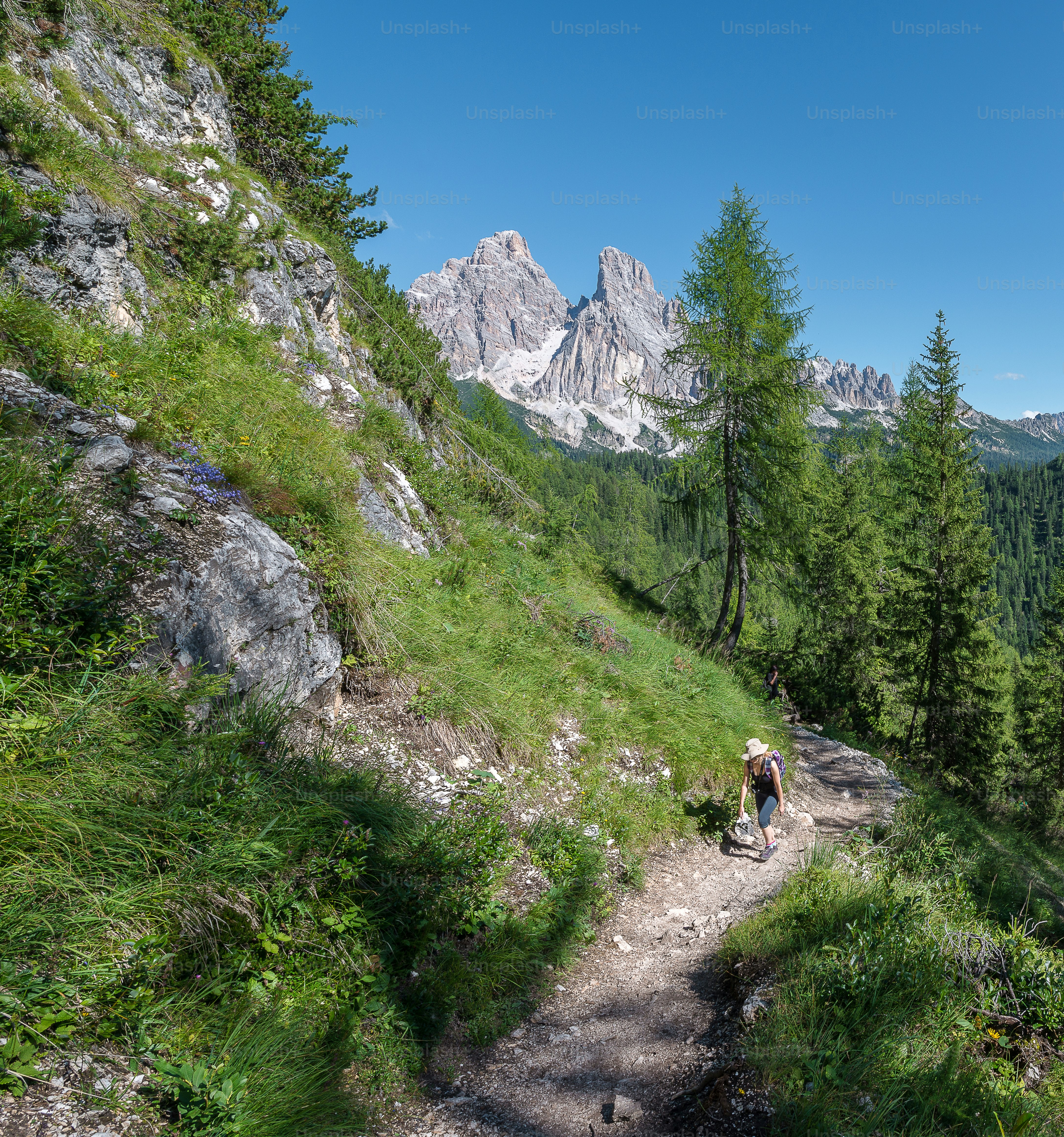 two people hiking up a trail in the mountains