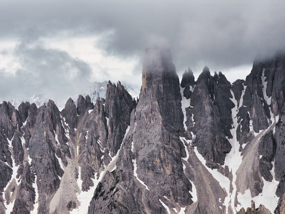 a group of mountains covered in snow under a cloudy sky