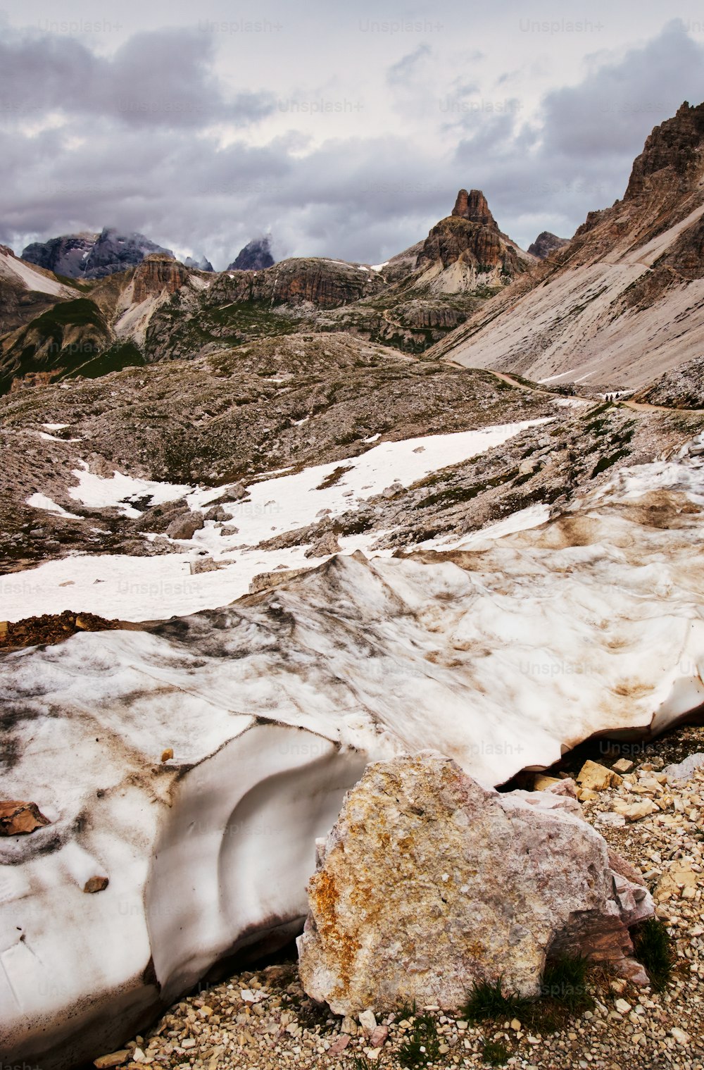 a mountain landscape with snow on the ground and rocks on the ground