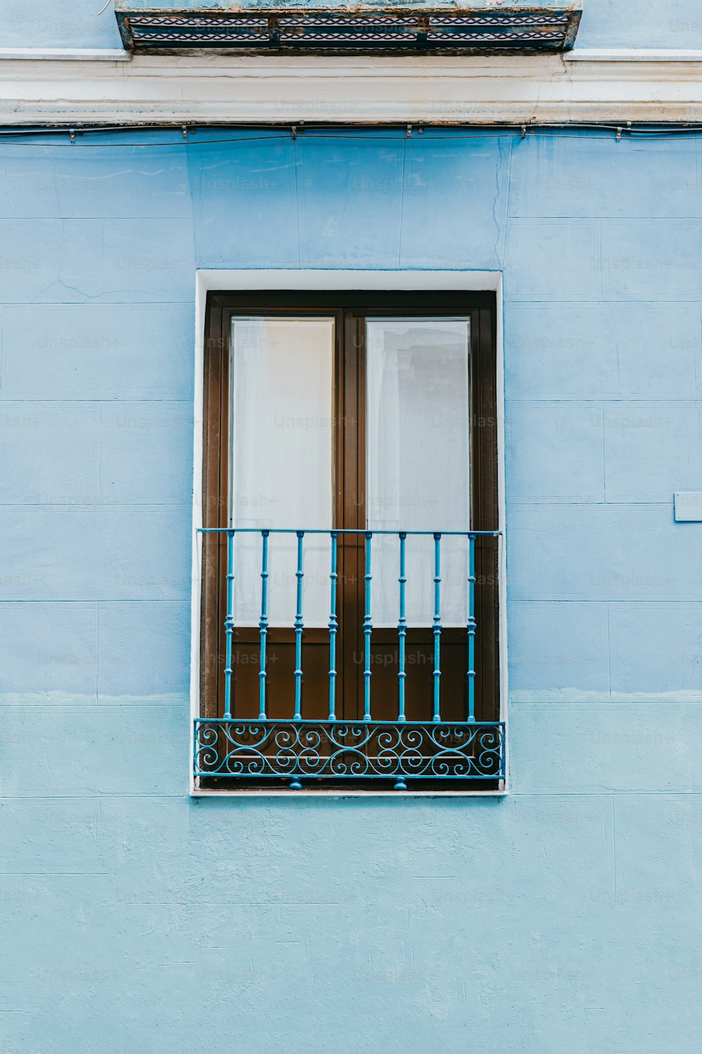 Un edificio azul con una ventana y un balcón