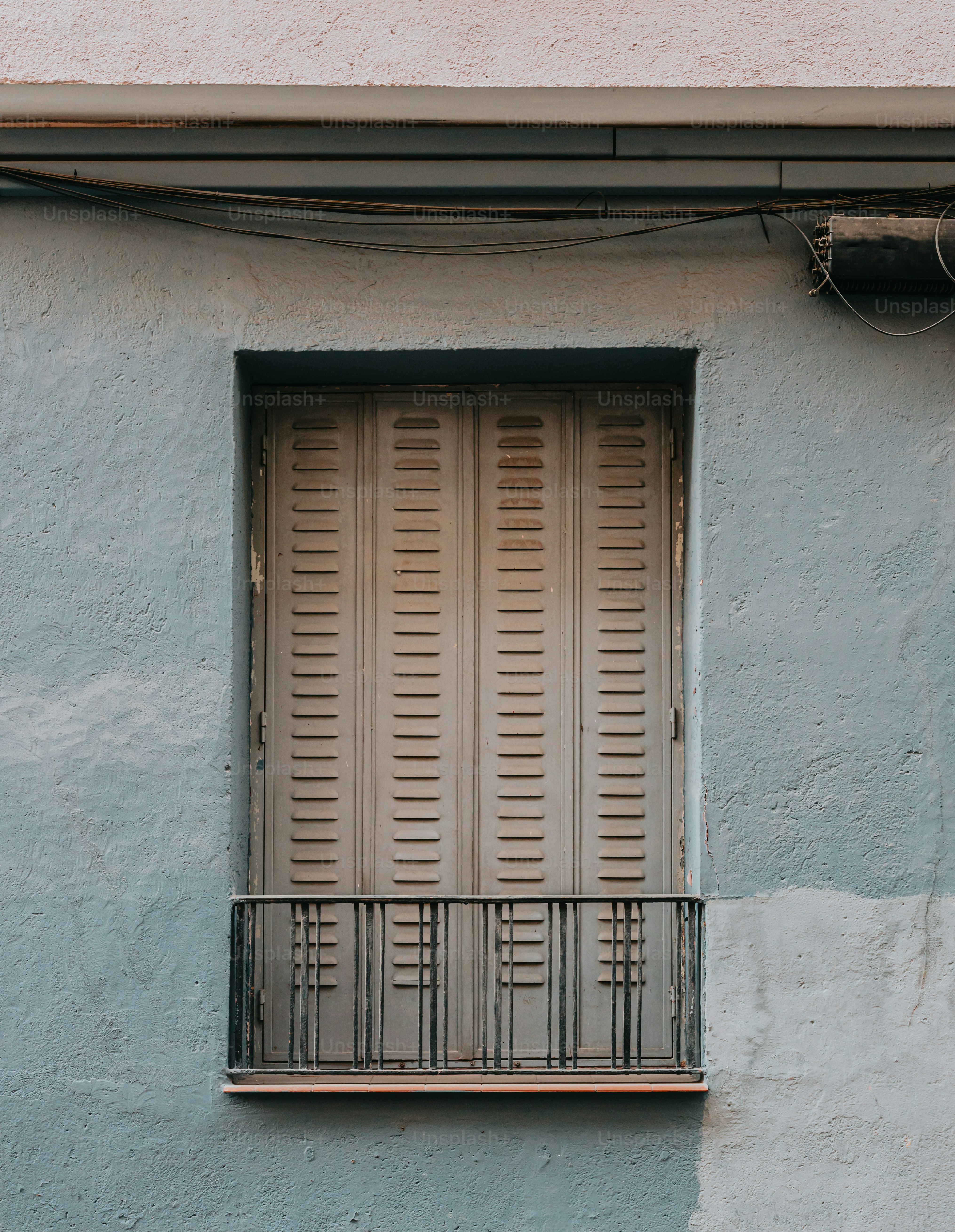 Un edificio azul con una ventana y un balcón