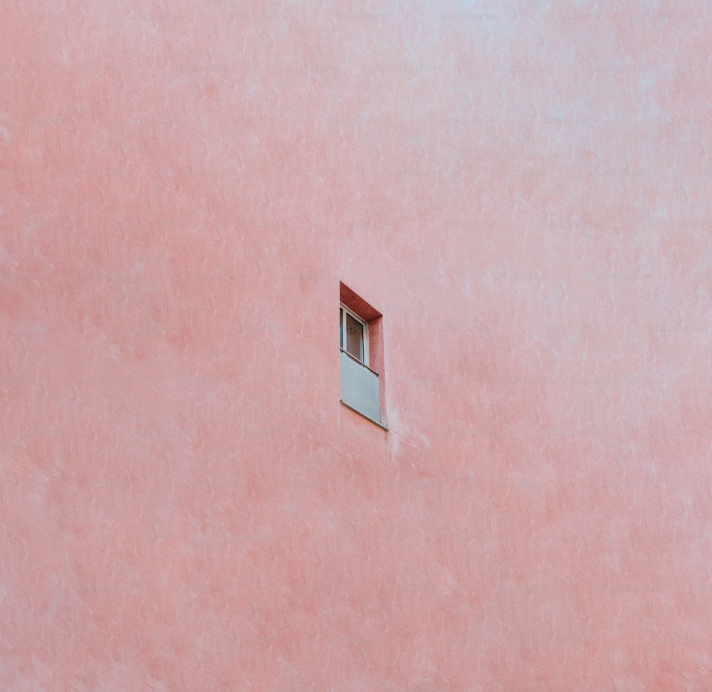 uma parede rosa com uma janela e uma pequena janela